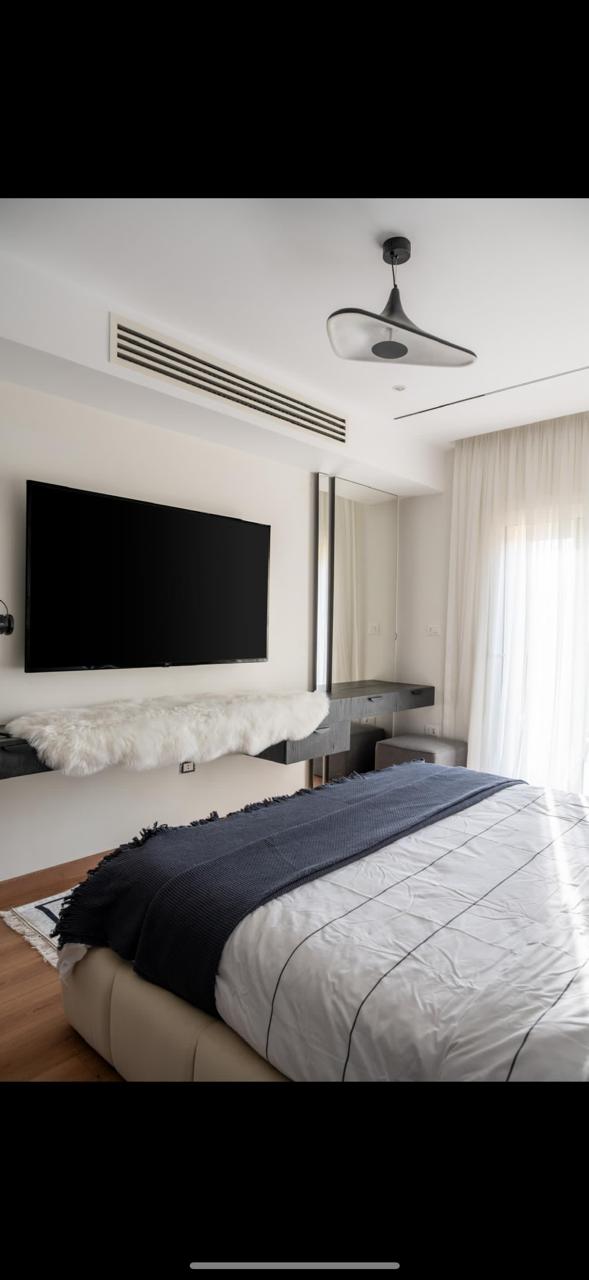 Chambre moderne avec grand écran et fenêtre lumineuse
