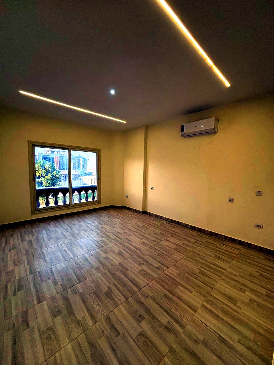 Pièce non meublée avec parquet et balcon